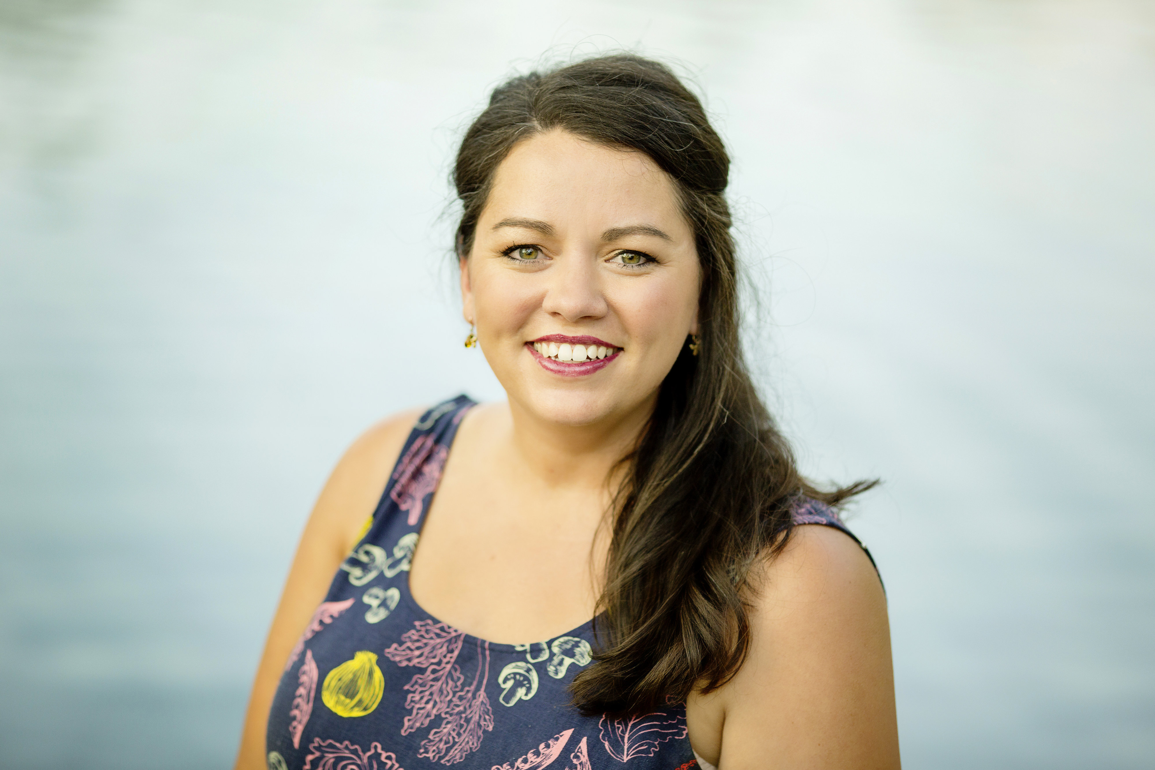 Lindie Huffman head shot in vegetable jumpsuit with blue background